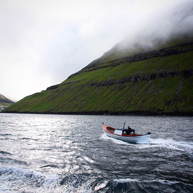 Misty mountains and rough seas, a boat sailing across the waves to Klaksvik, Faroe Islands