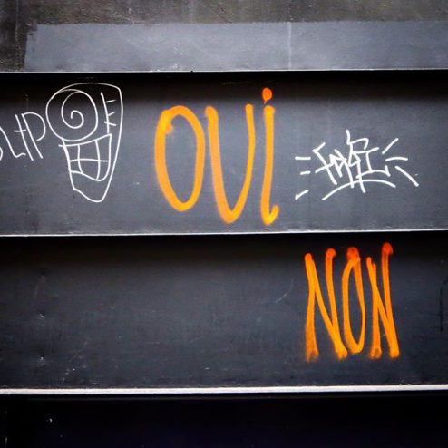 Oui Non graffiti spray art in Paris, France, orange against a black door